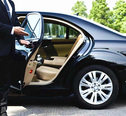 Luxury Limo Transportation service with professional chauffeur opening the door of a sleek black car.