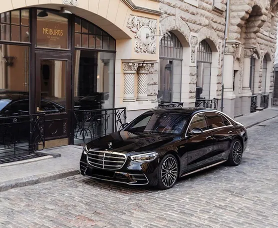 Black luxury car parked outside a stylish building, showcasing modern urban transportation.