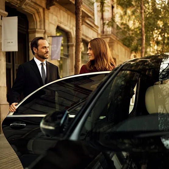 Transportation service with a chauffeur assisting passenger at a stylish urban location.