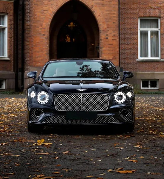 Stylish Bentley car parked, showing off modern transportation in front of a classic brick building.