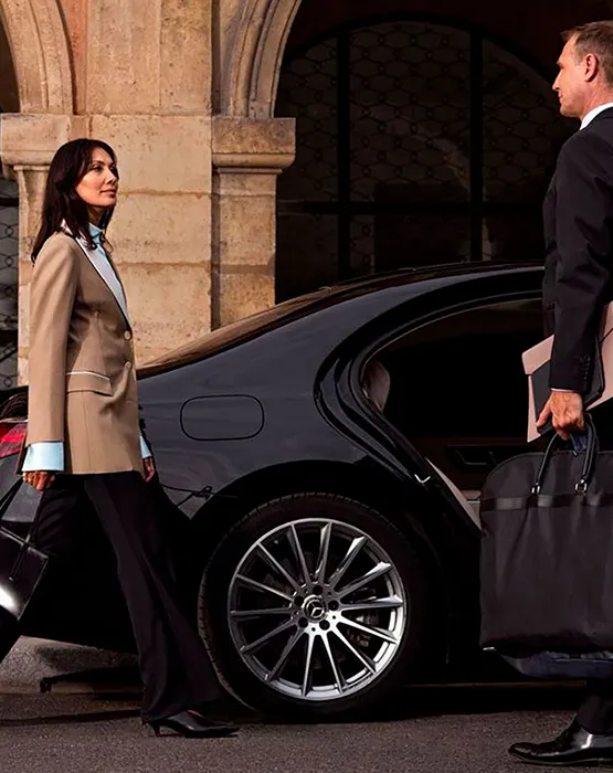 Luxury transportation scene featuring professionals approaching a sleek black car with stylish design.